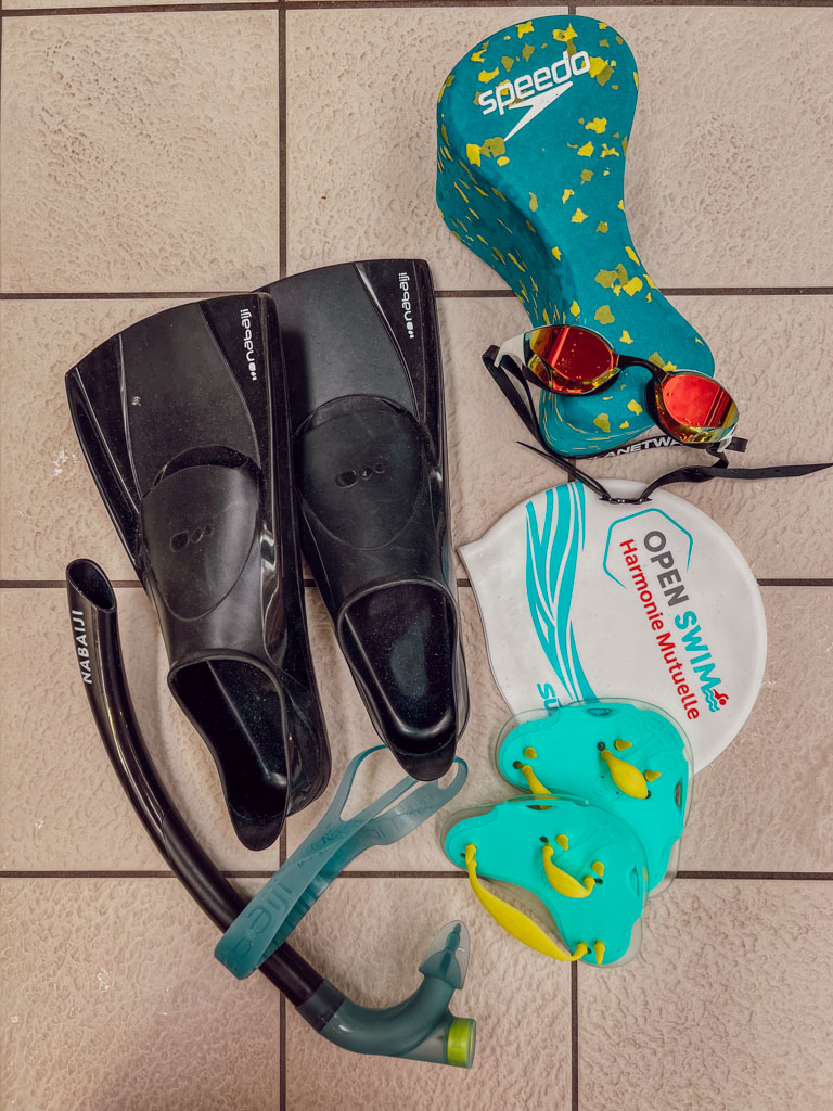 Pour commencer la natation, inutile d’investir dans un équipement ultra technique : un maillot de bain confortable, une bonne paire de lunettes, un bonnet et des tongs suffisent largement pour tes premières séances. Avec le temps, tu pourras éventuellement ajouter quelques accessoires de natation comme des palmes, un pull buoy ou un tuba frontal pour varier les entraînements et travailler ta technique. En natation, le matériel idéal n’est pas celui qui impressionne au bord du bassin, mais celui qui te donne envie de revenir nager sereinement.
